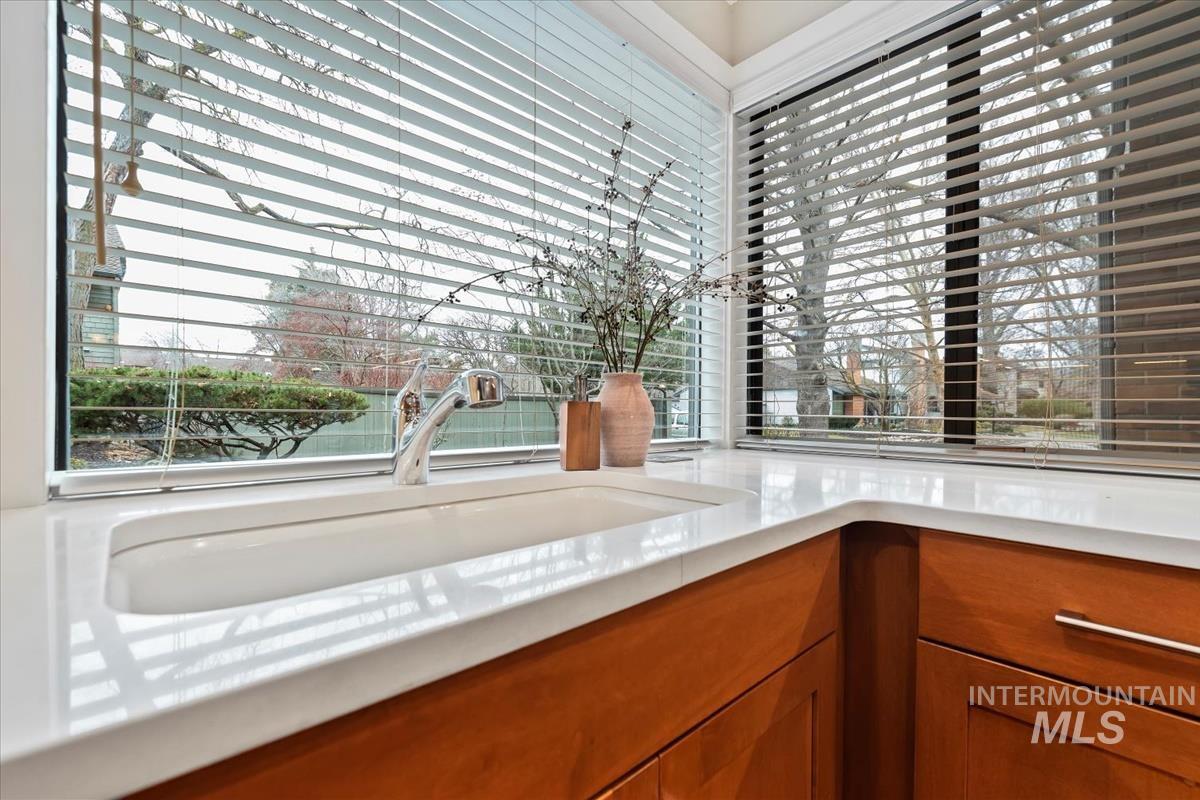 Kitchen view of brown cabinetry and light stone countertops