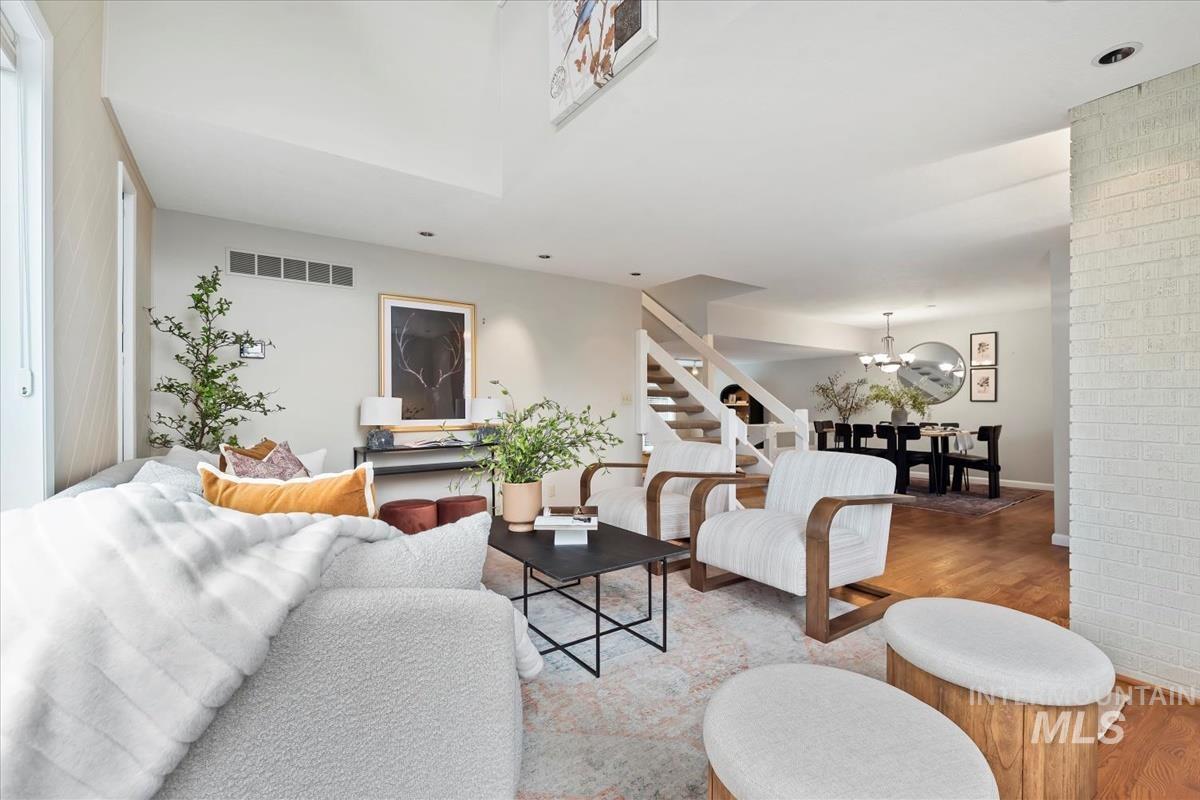 Living room with wood finished floors, stairway, and a chandelier