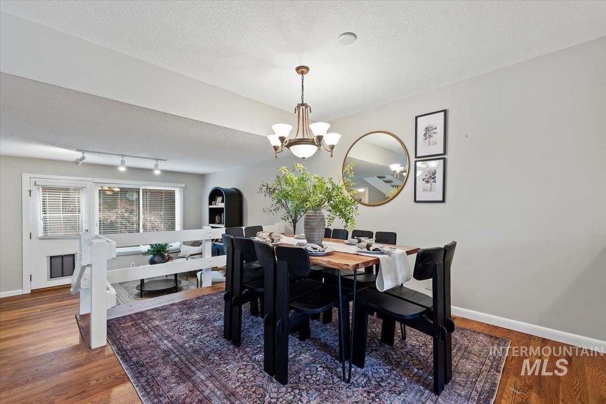 Dining room featuring dark wood-type flooring, a chandelier, and a textured ceiling