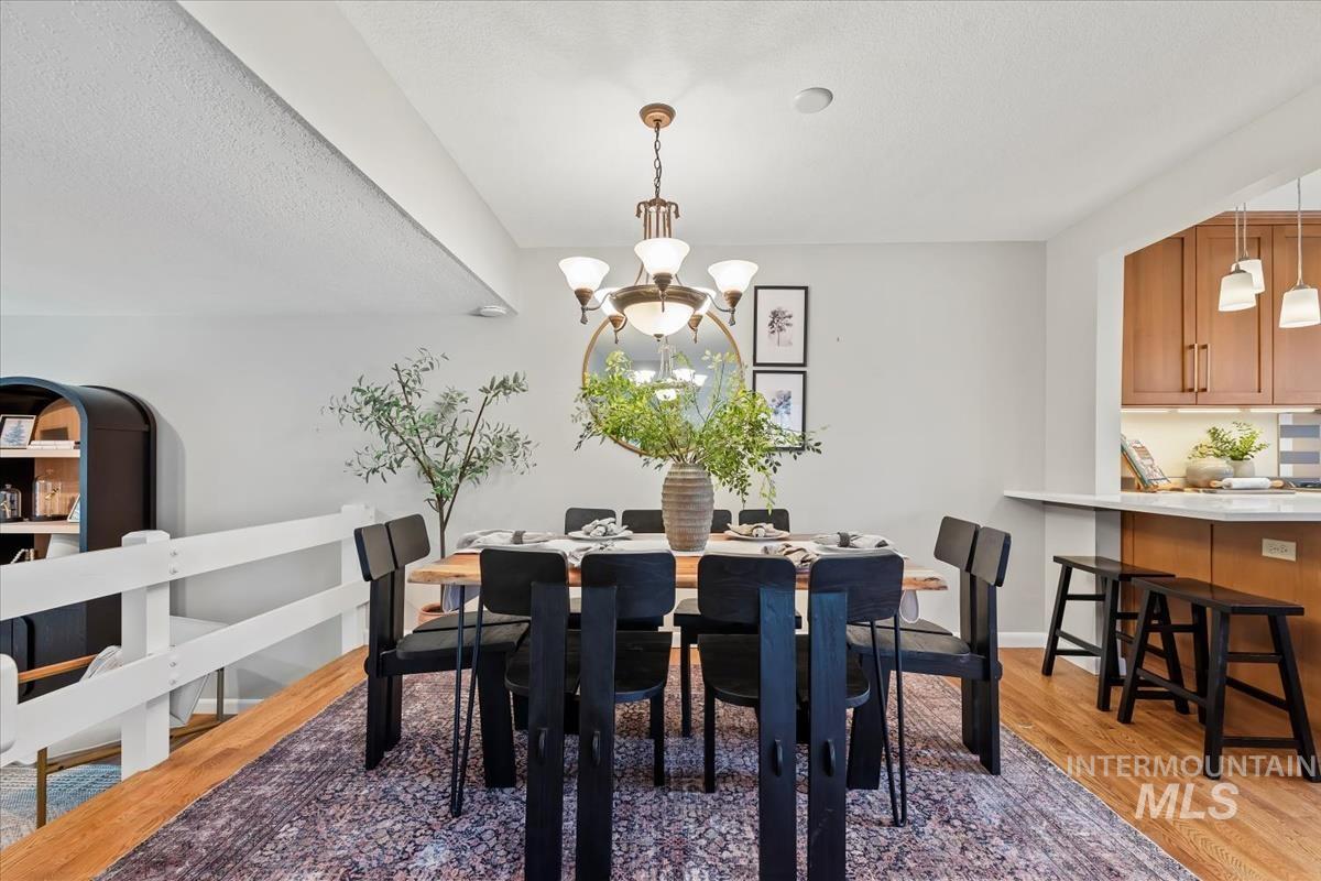 Dining room with light wood finished floors, a chandelier, and a textured ceiling
