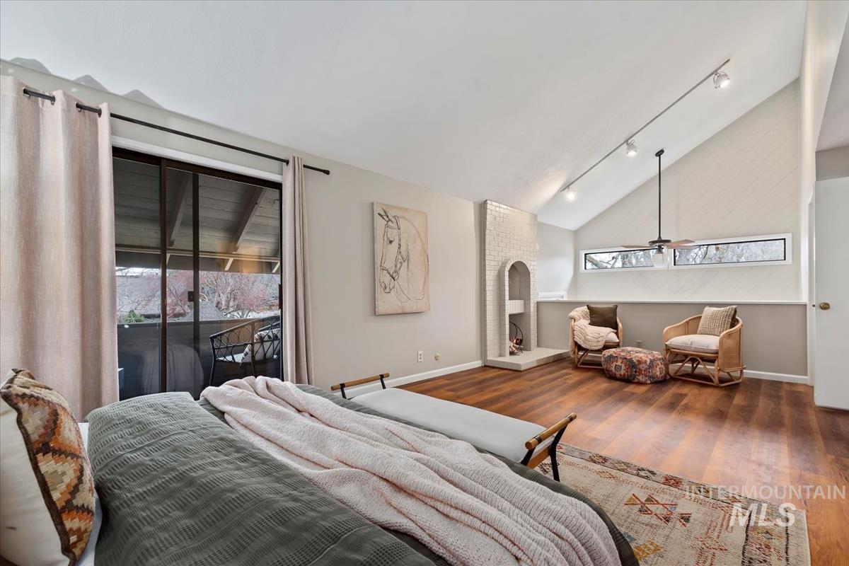 Bedroom featuring rail lighting, wood finished floors, access to exterior, and high vaulted ceiling
