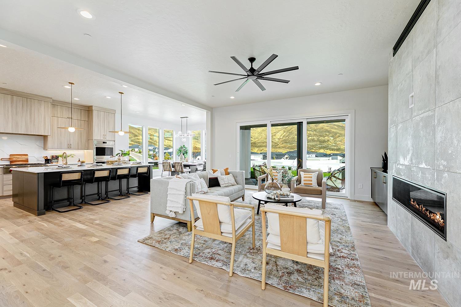 Living area featuring light wood-style flooring, a ceiling fan, healthy amount of natural light, recessed lighting, and a tiled fireplace
