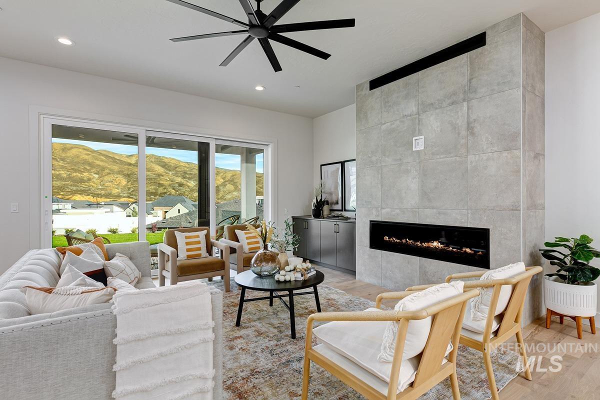 Living room featuring light wood-type flooring, a fireplace, a ceiling fan, recessed lighting, and a mountain view