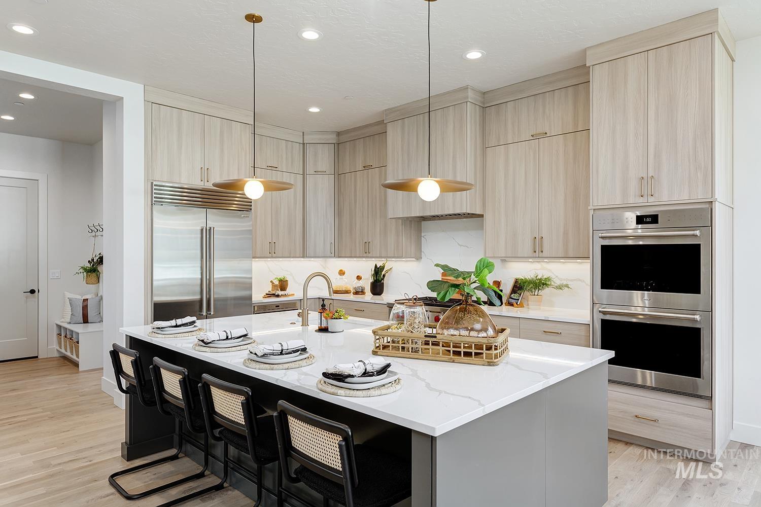Kitchen featuring modern cabinets, light brown cabinets, light stone countertops, appliances with stainless steel finishes, and light wood-style floors