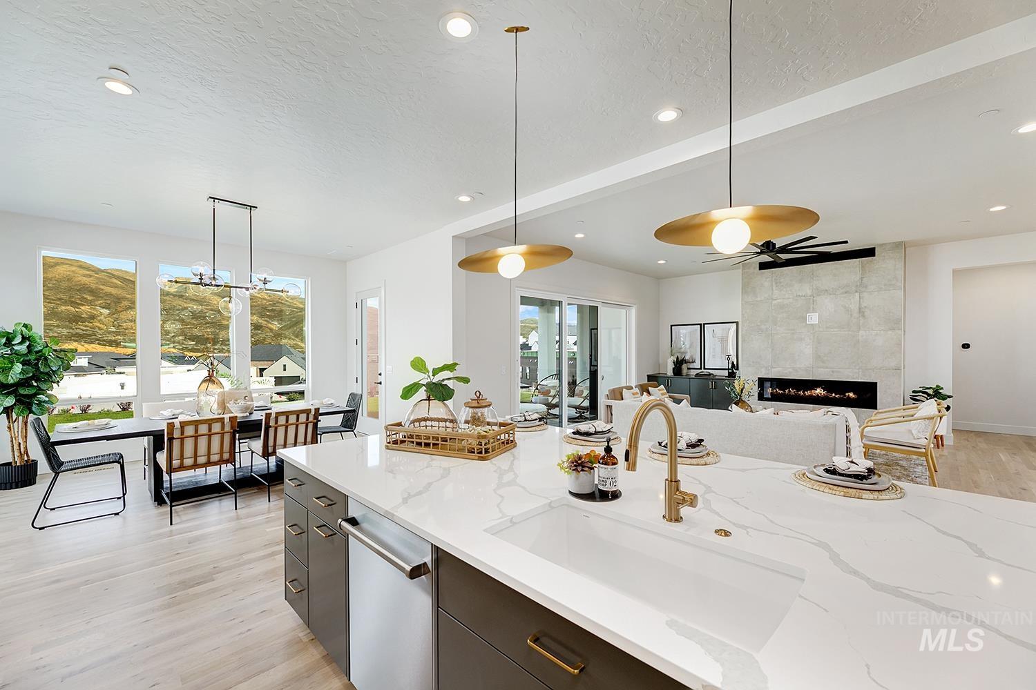 Kitchen featuring light wood-style floors, pendant lighting, a textured ceiling, a tiled fireplace, and recessed lighting