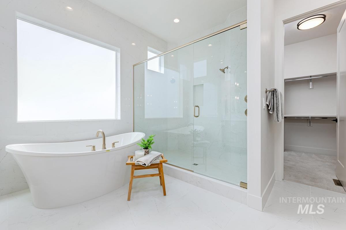 Full bath featuring a freestanding bath, a stall shower, a spacious closet, and recessed lighting