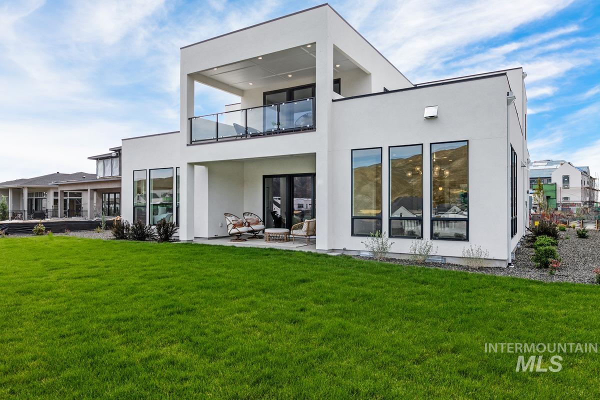 Rear view of property featuring a patio area, a lawn, a balcony, and stucco siding