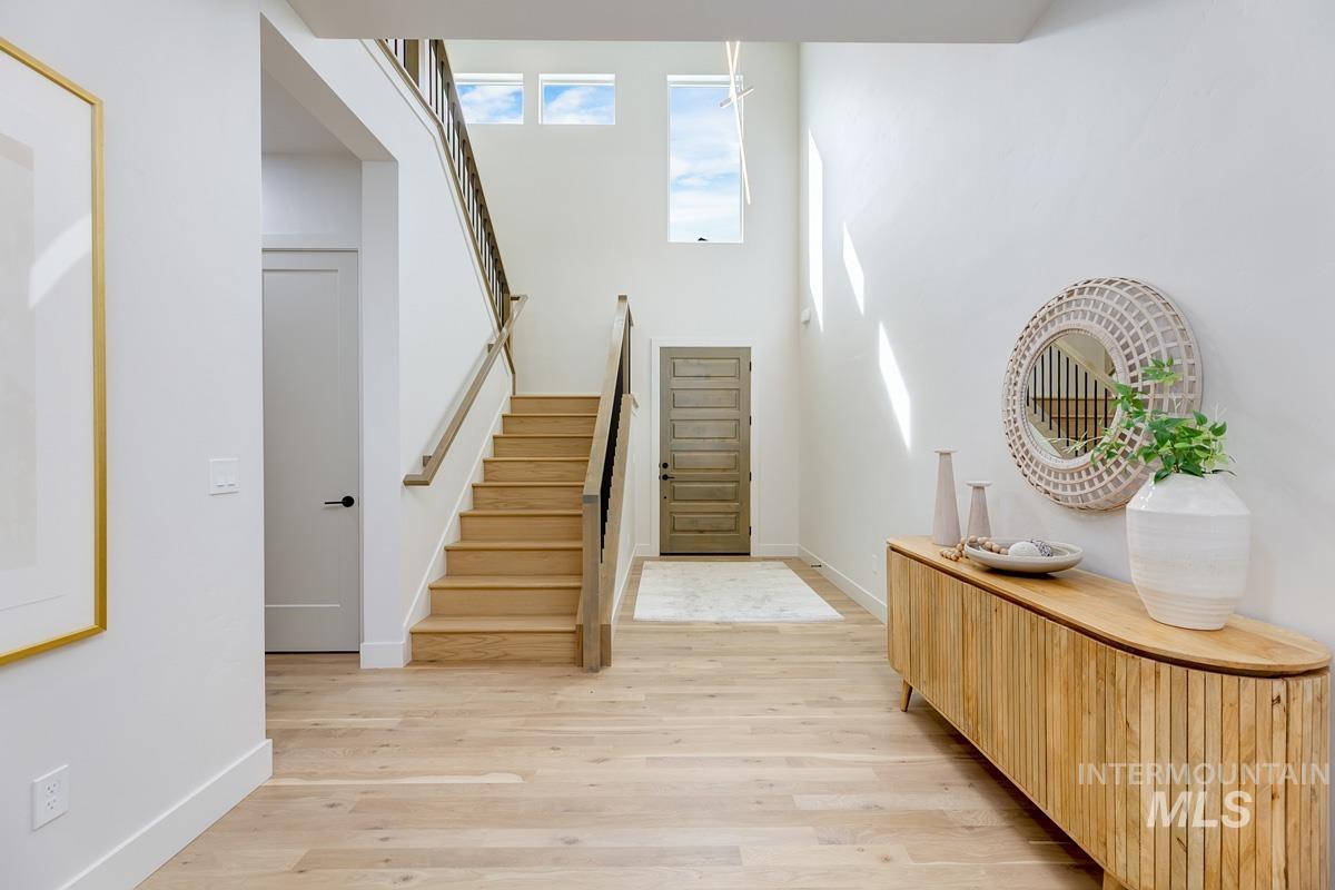 Entryway featuring stairs, light wood finished floors, and a towering ceiling