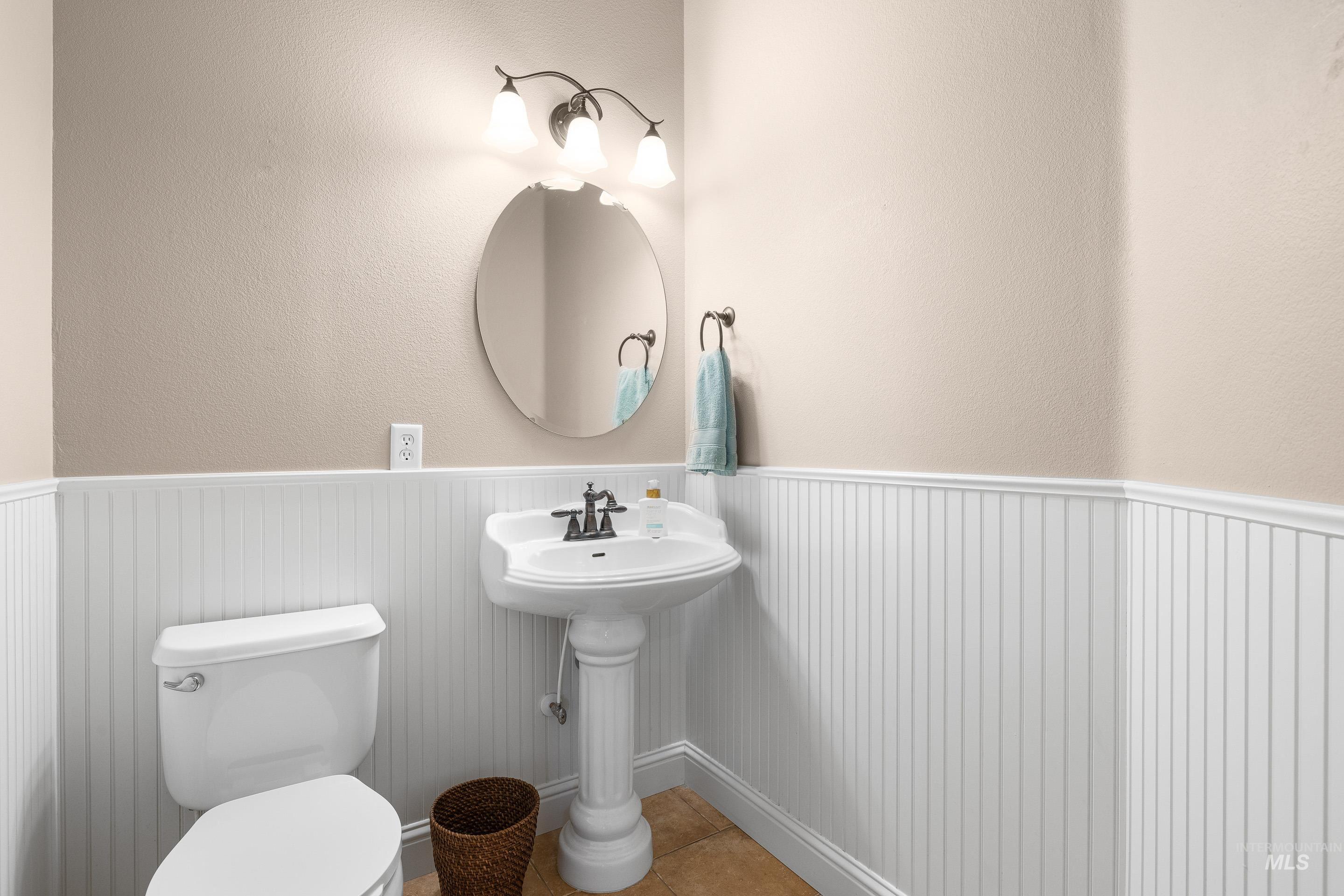 Bathroom with wainscoting, a textured wall, and tile patterned flooring
