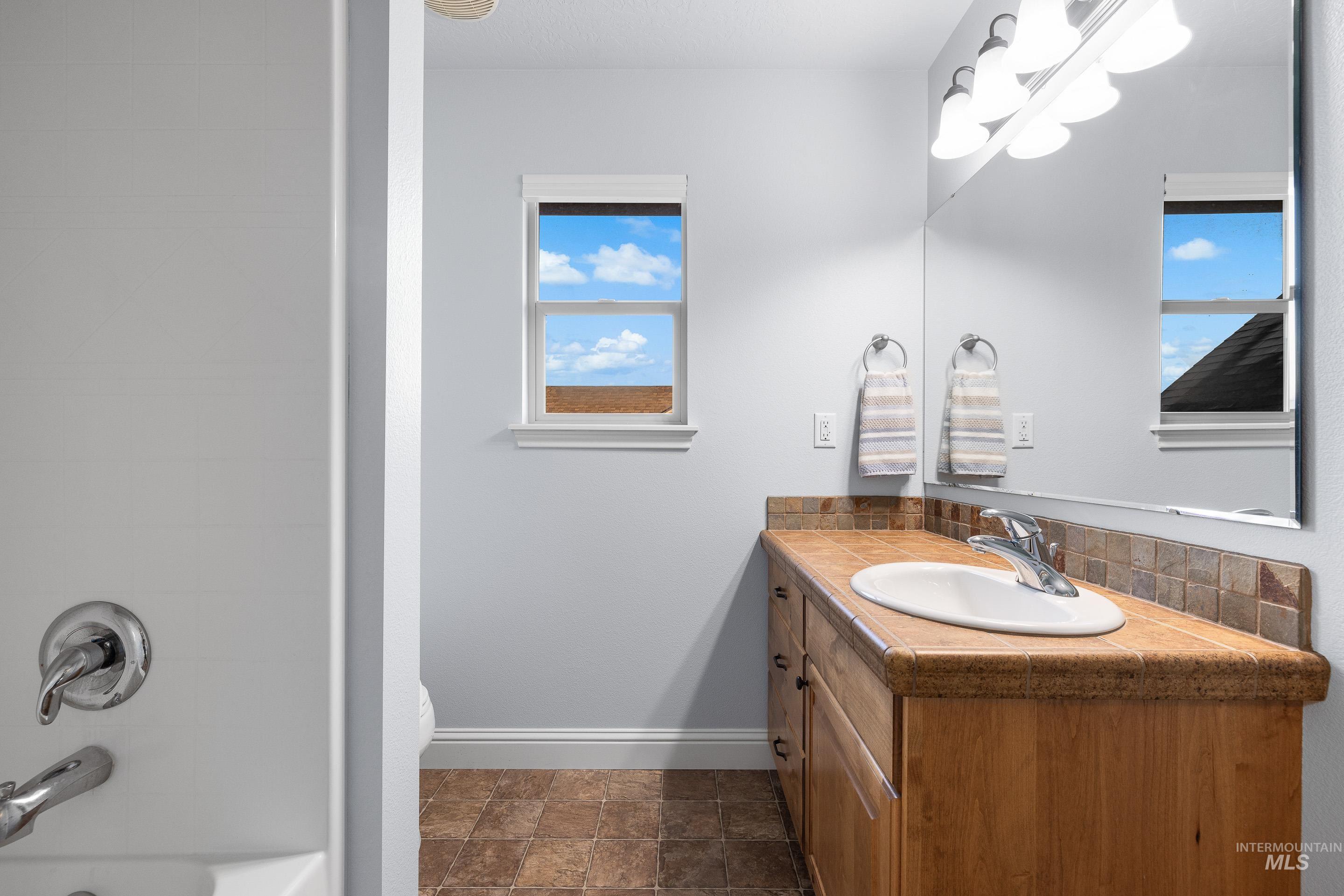 Full bath with vanity, stone finish floors, and tub / shower combination