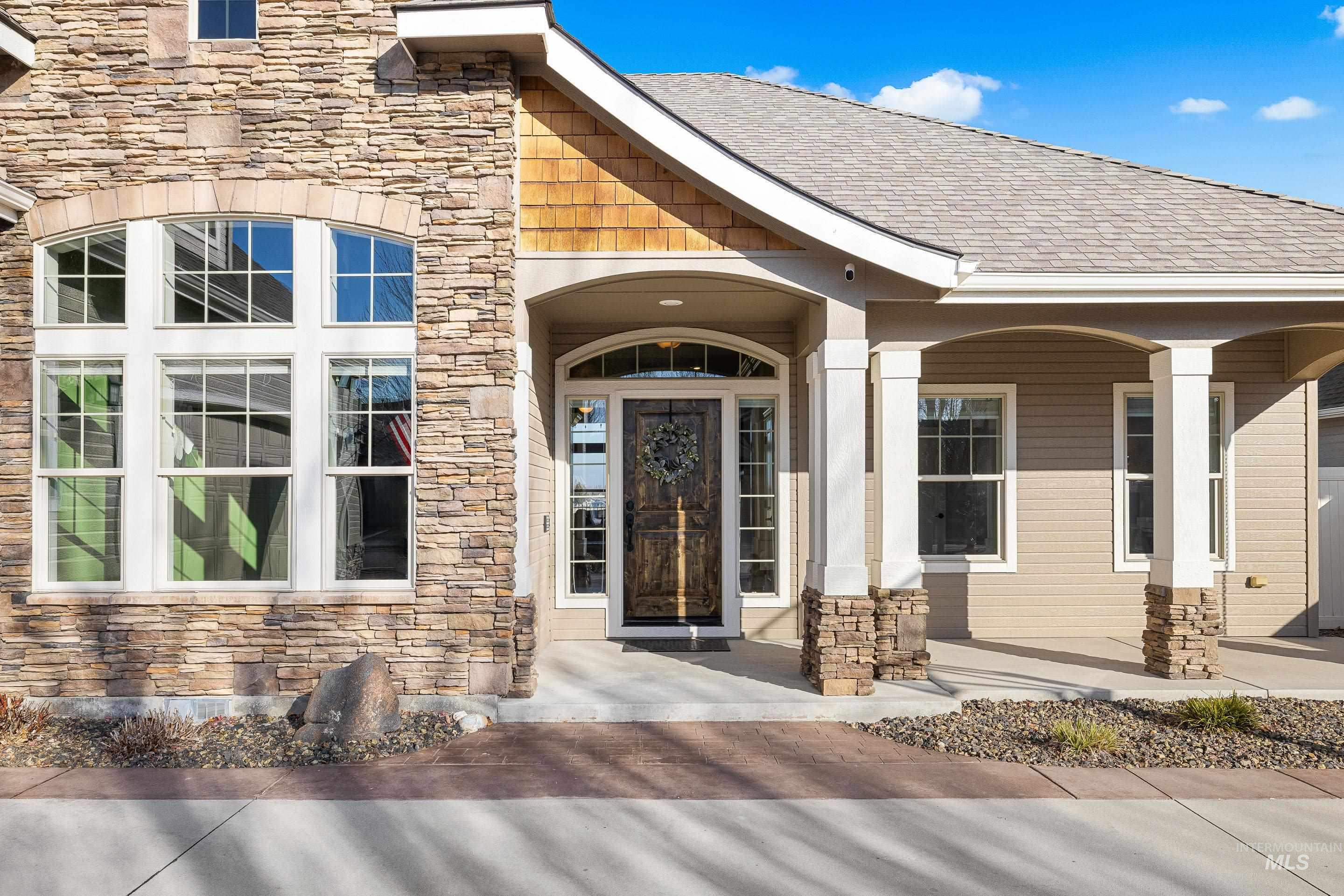 Entrance to property with stone siding, a porch, and roof with shingles