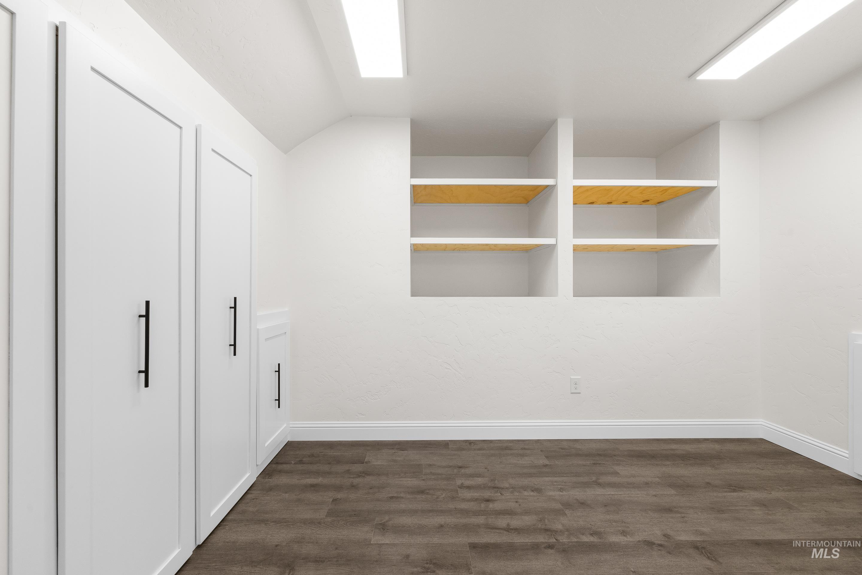Interior space featuring dark wood-style flooring and baseboards