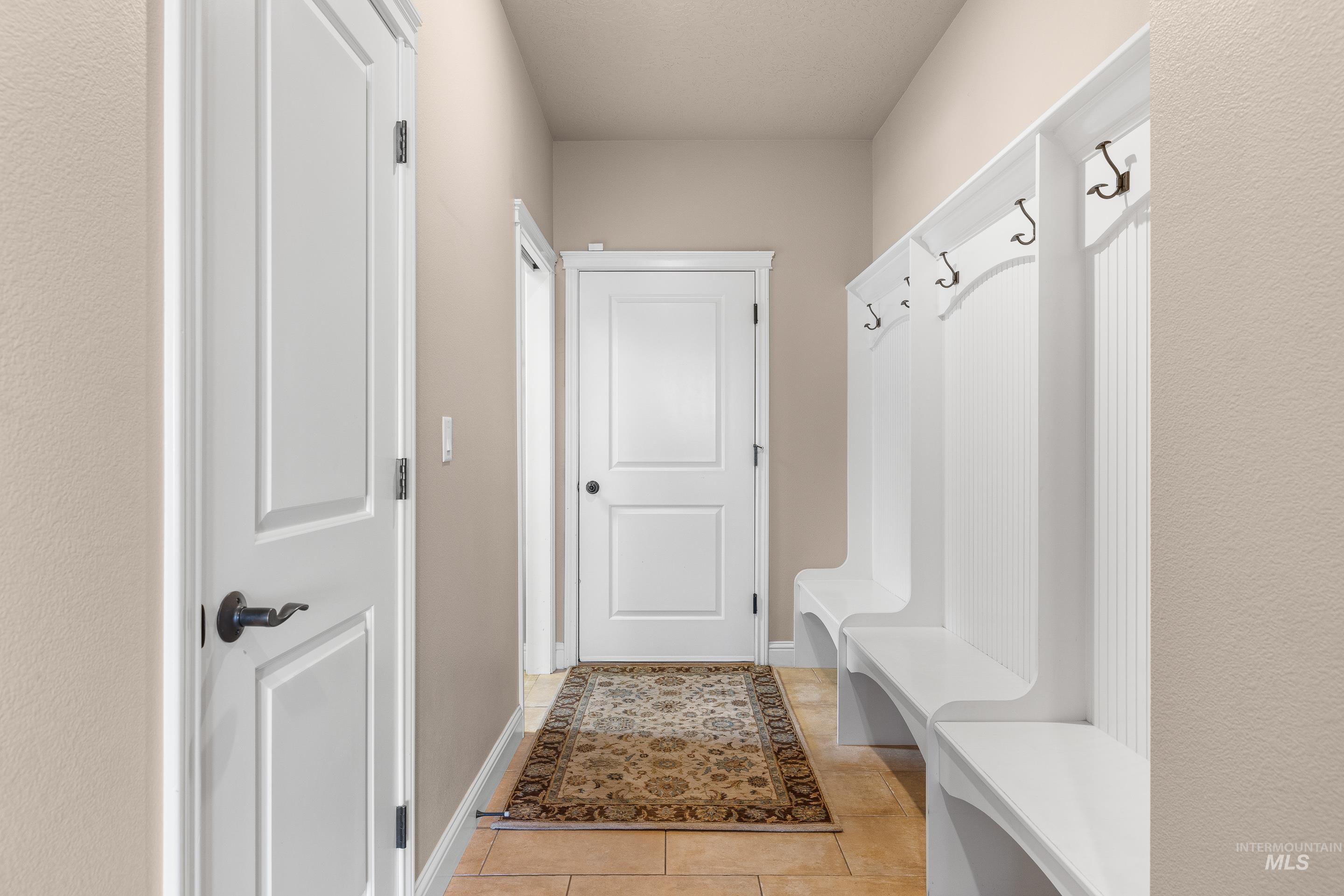 Mudroom with light tile patterned flooring and a textured wall