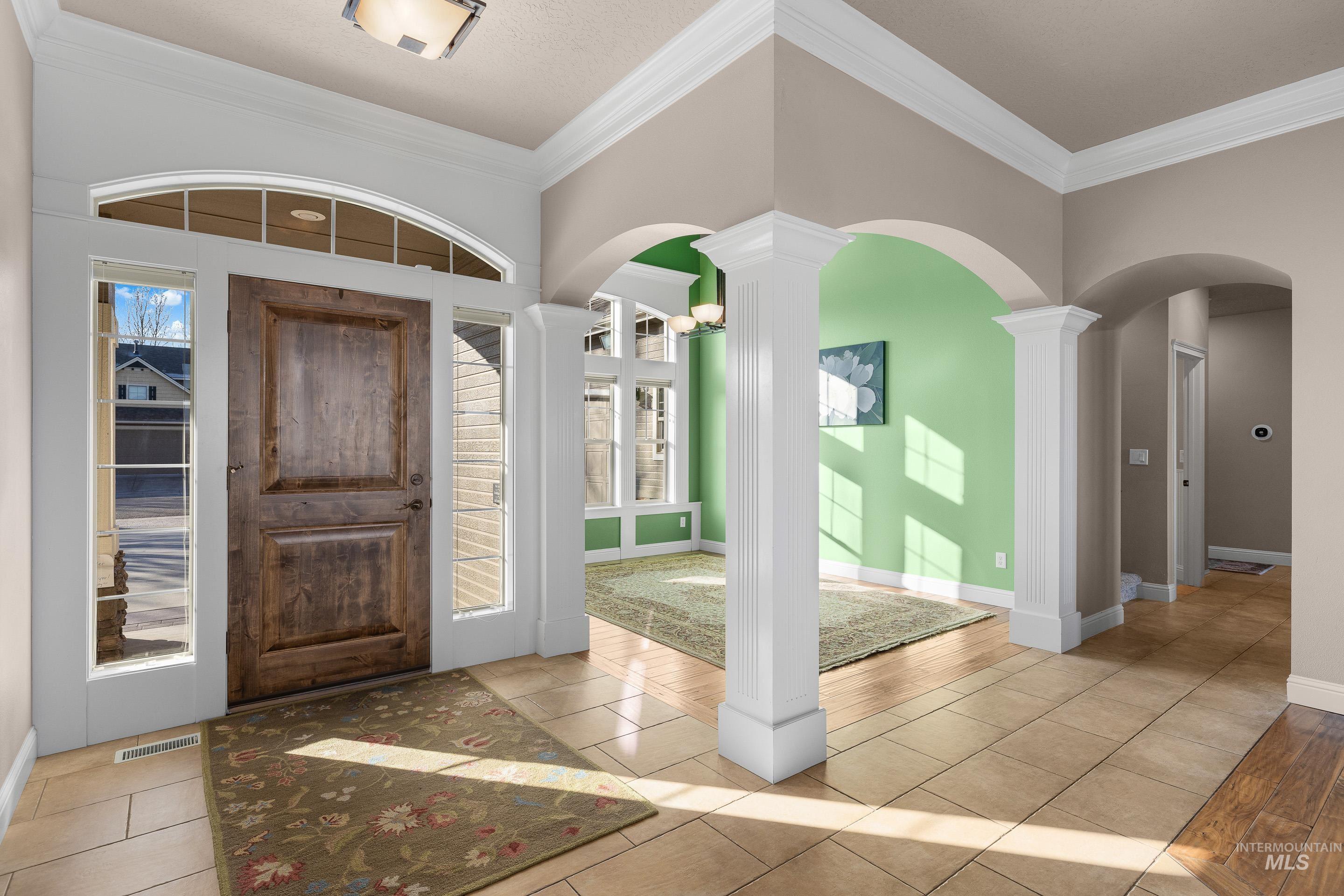 Foyer entrance featuring arched walkways, crown molding, and light tile patterned flooring