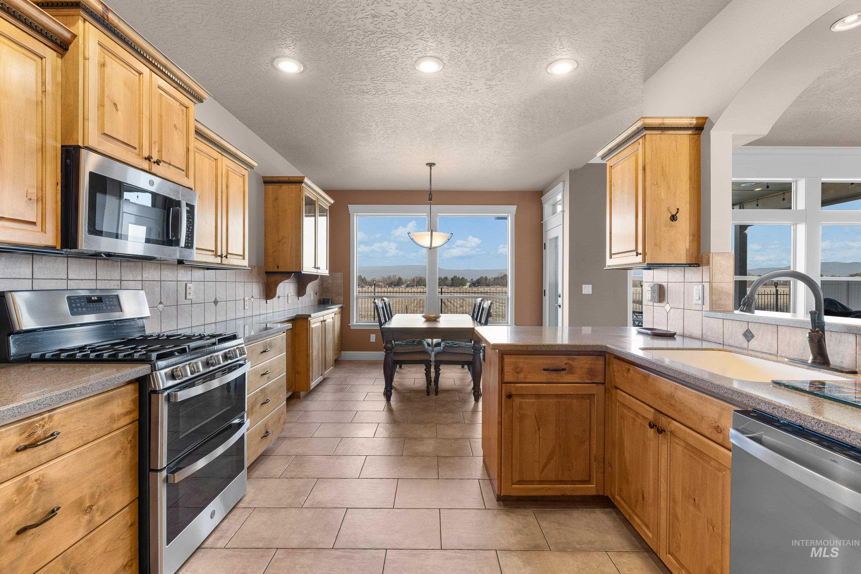 Kitchen featuring appliances with stainless steel finishes, recessed lighting, backsplash, pendant lighting, and a textured ceiling