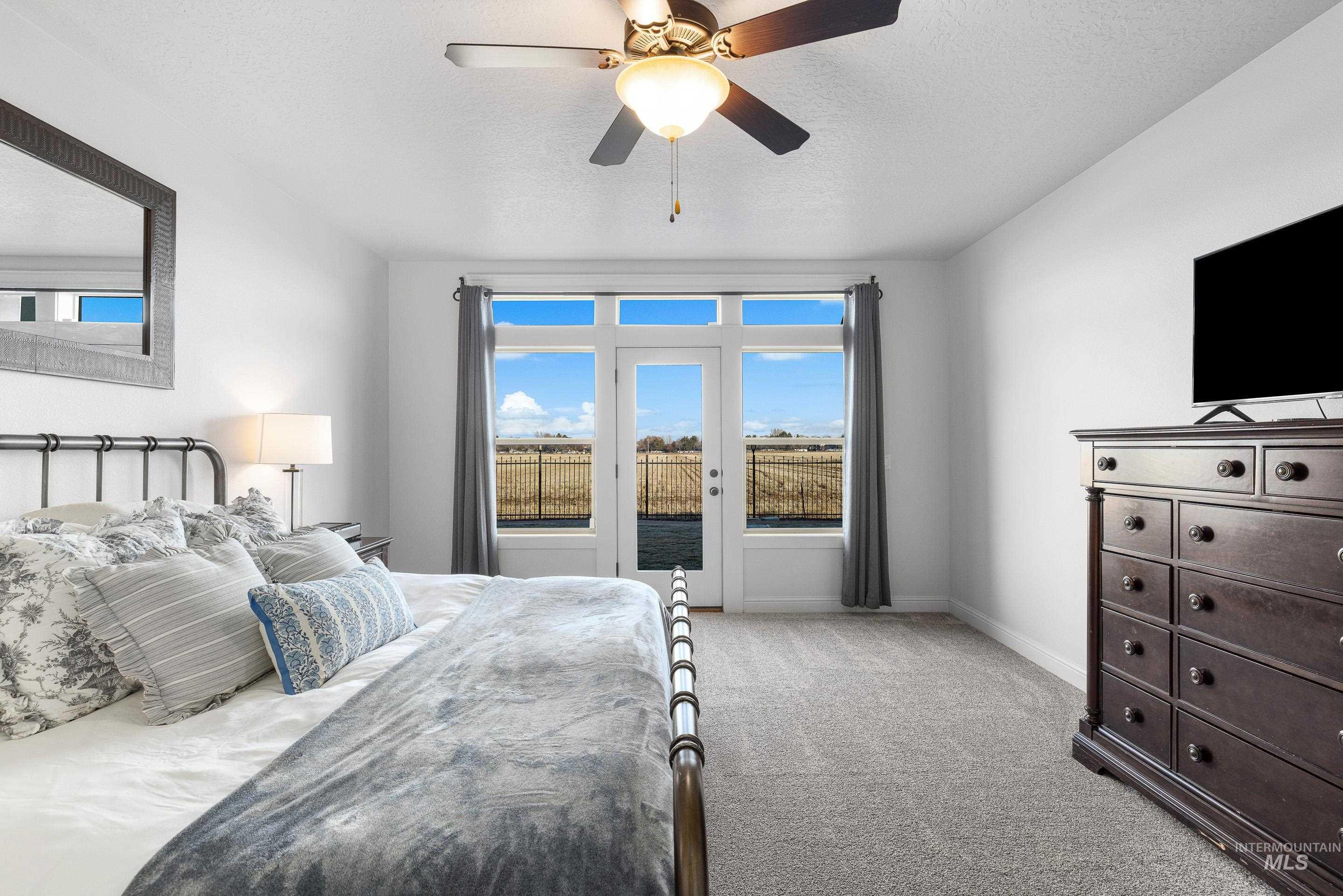 Bedroom featuring access to exterior, ceiling fan, light carpet, and a textured ceiling