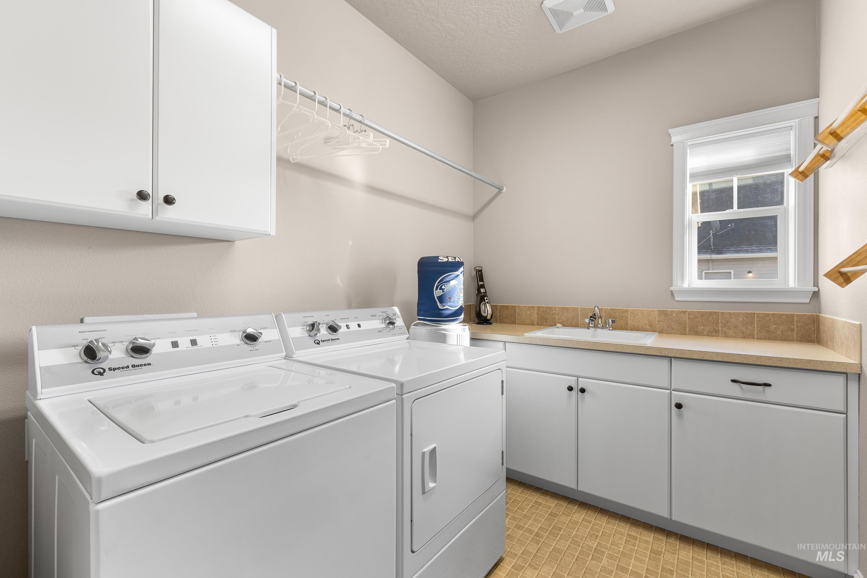 Washroom featuring cabinet space, washer and clothes dryer, and a textured ceiling
