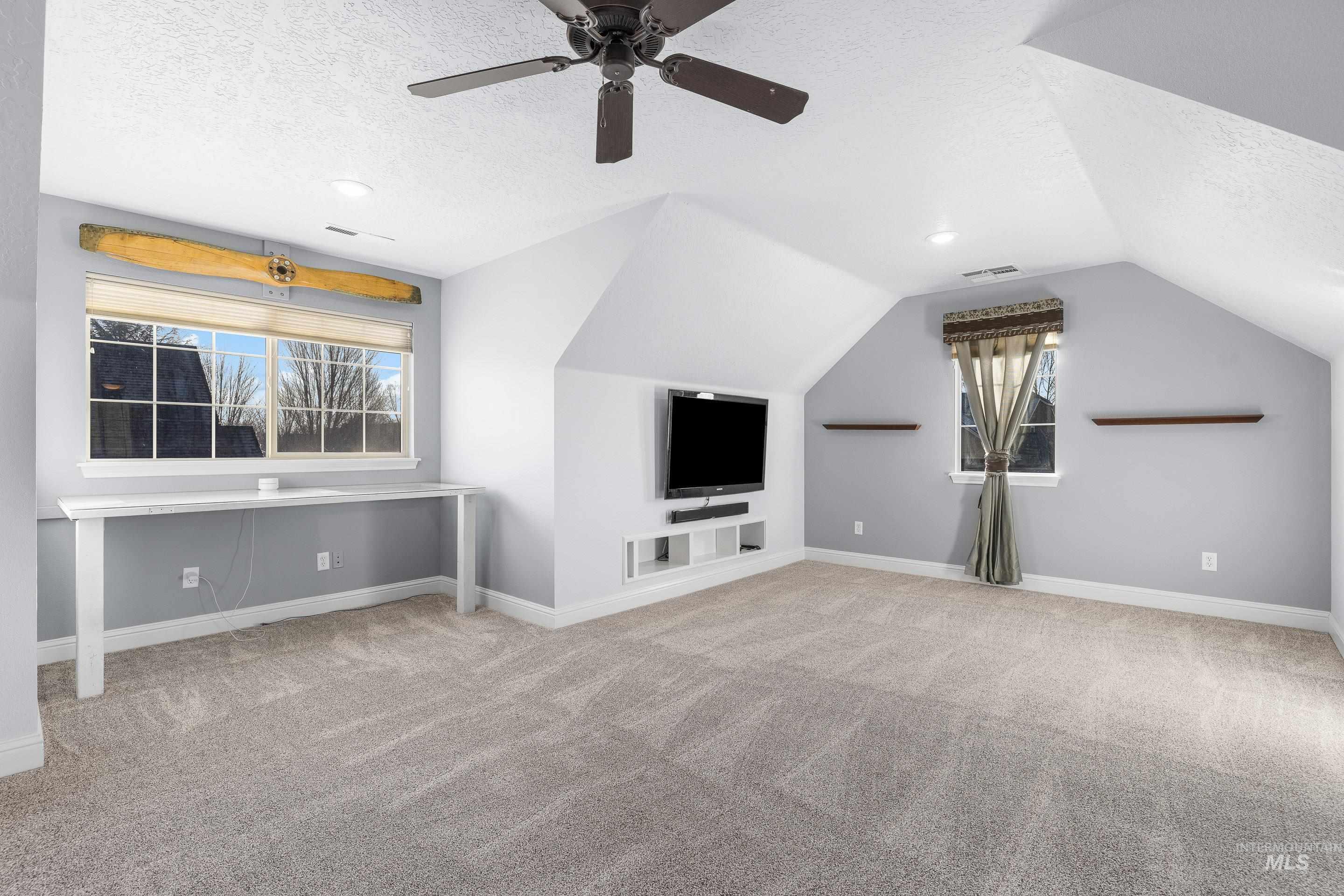 Additional living space featuring a textured ceiling, light carpet, and vaulted ceiling