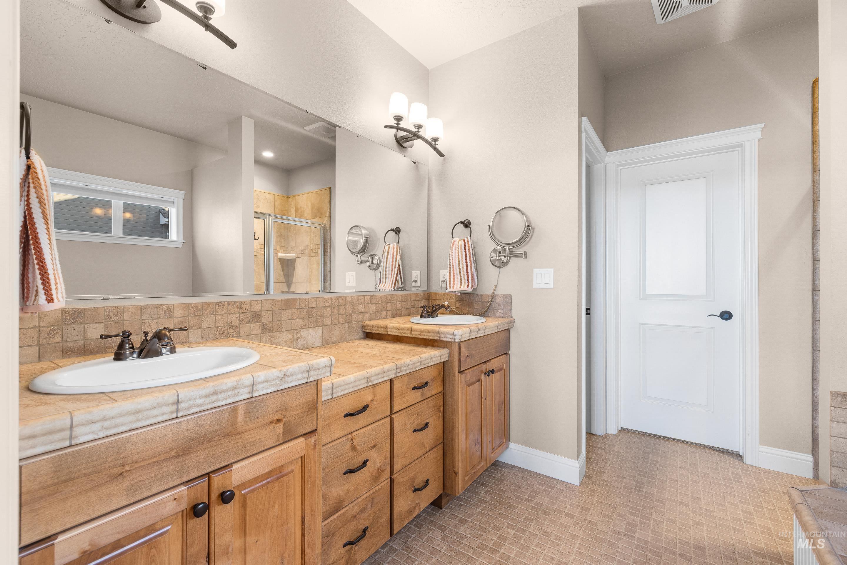 Full bath featuring a shower stall and double vanity