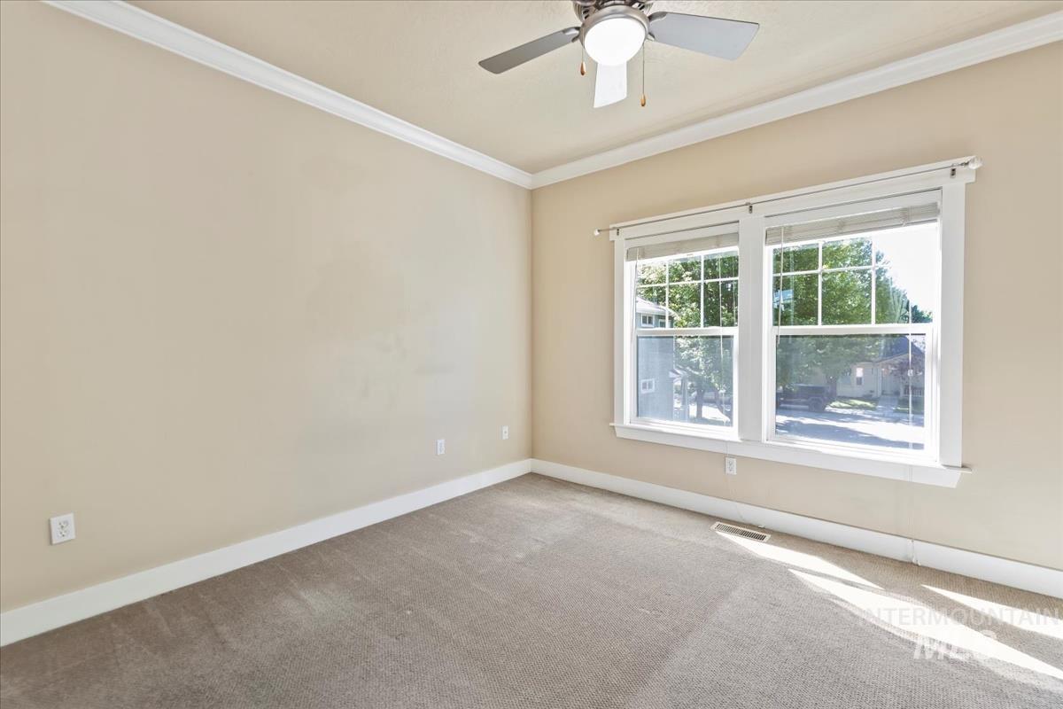 Carpeted spare room featuring ornamental molding and ceiling fan