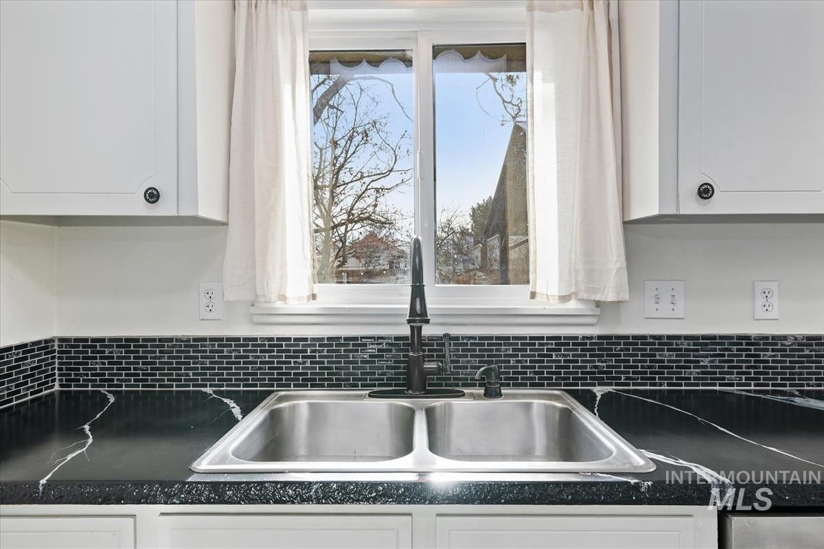 Kitchen view of dark countertops and white cabinets