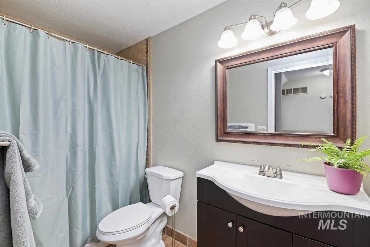 Full bathroom featuring vanity, a shower with shower curtain, a textured wall, and a textured ceiling
