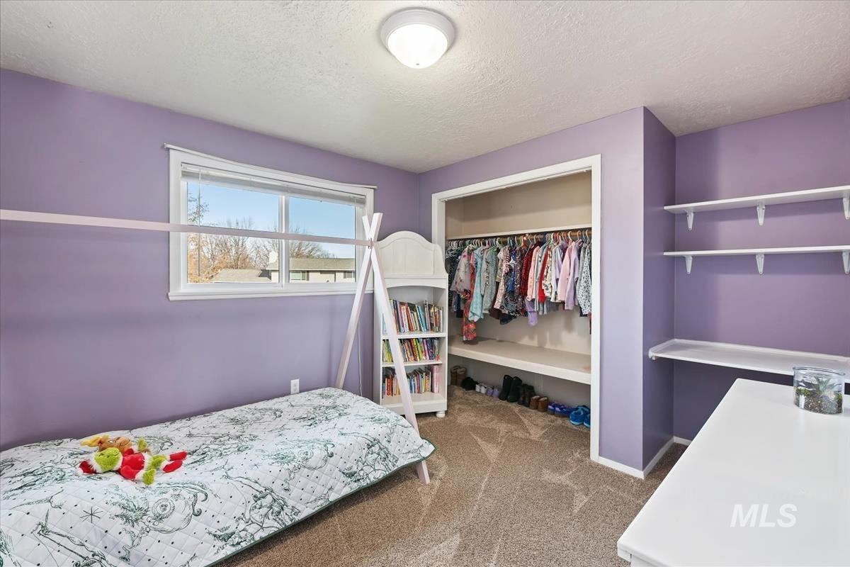 Bedroom with a textured ceiling, carpet floors, and a closet