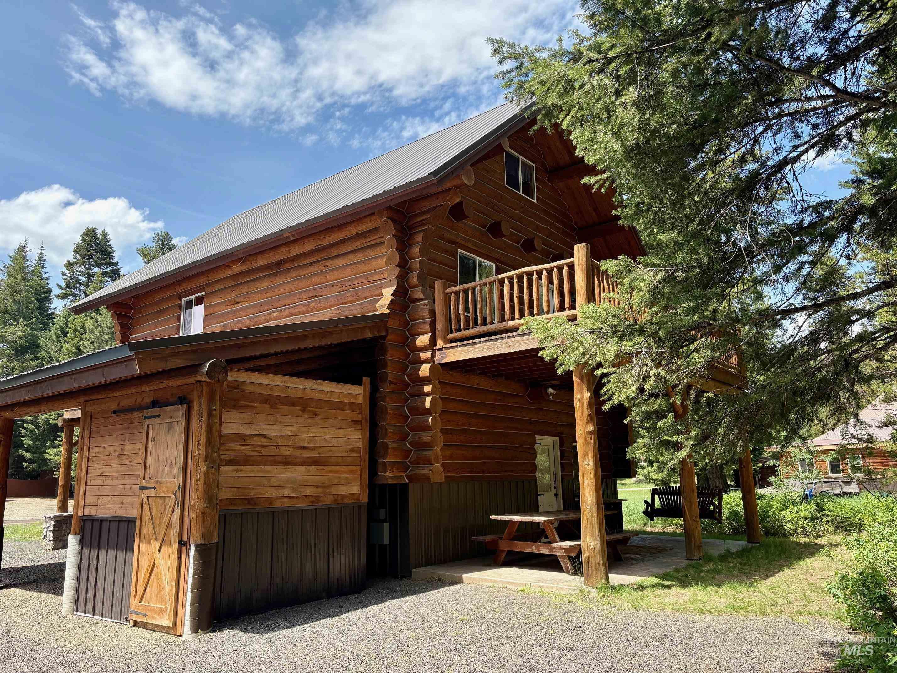 View of property exterior featuring a patio area, log siding, and a balcony