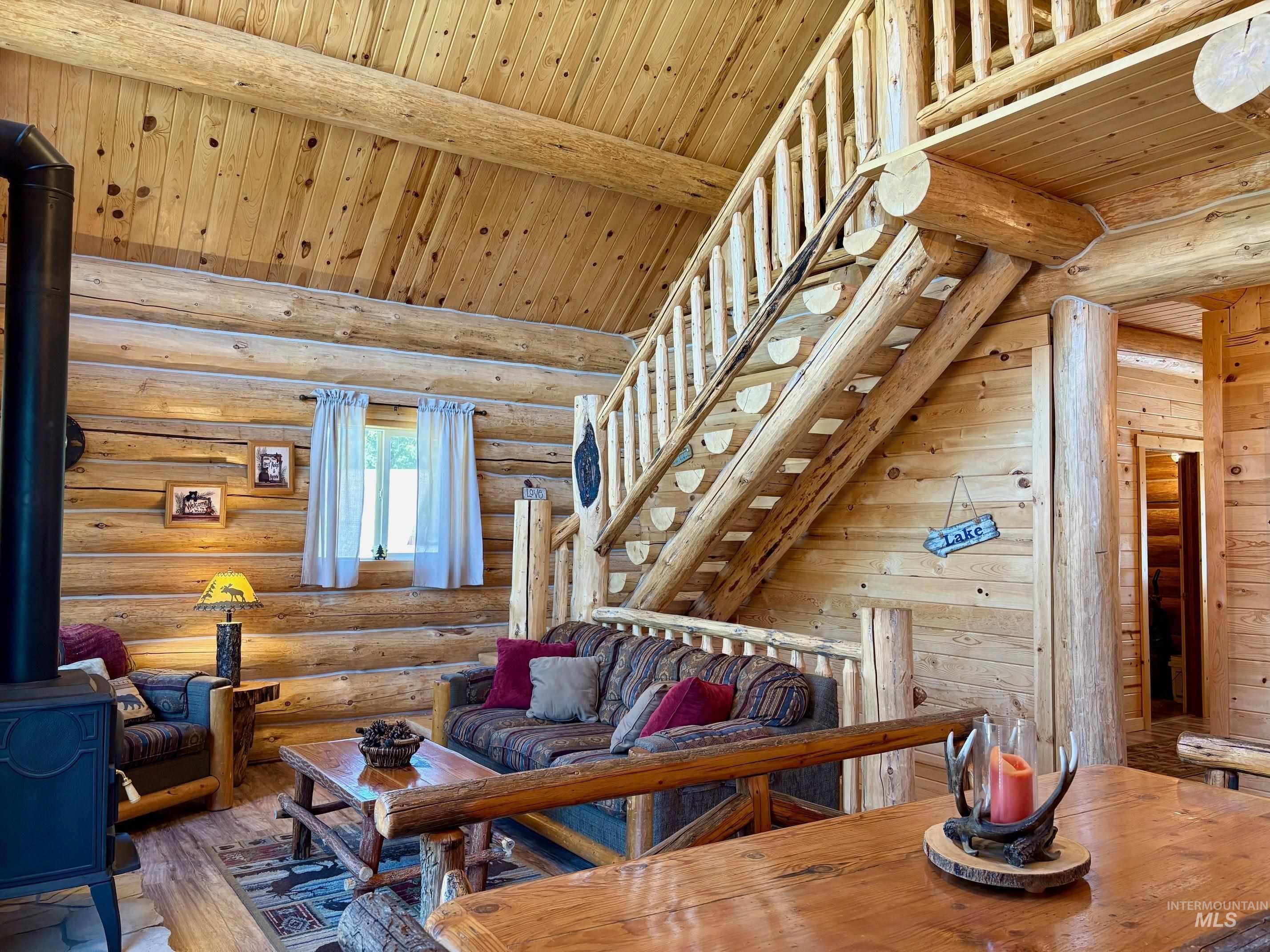Living room featuring a wood stove, wood ceiling, wood-type flooring, and log walls