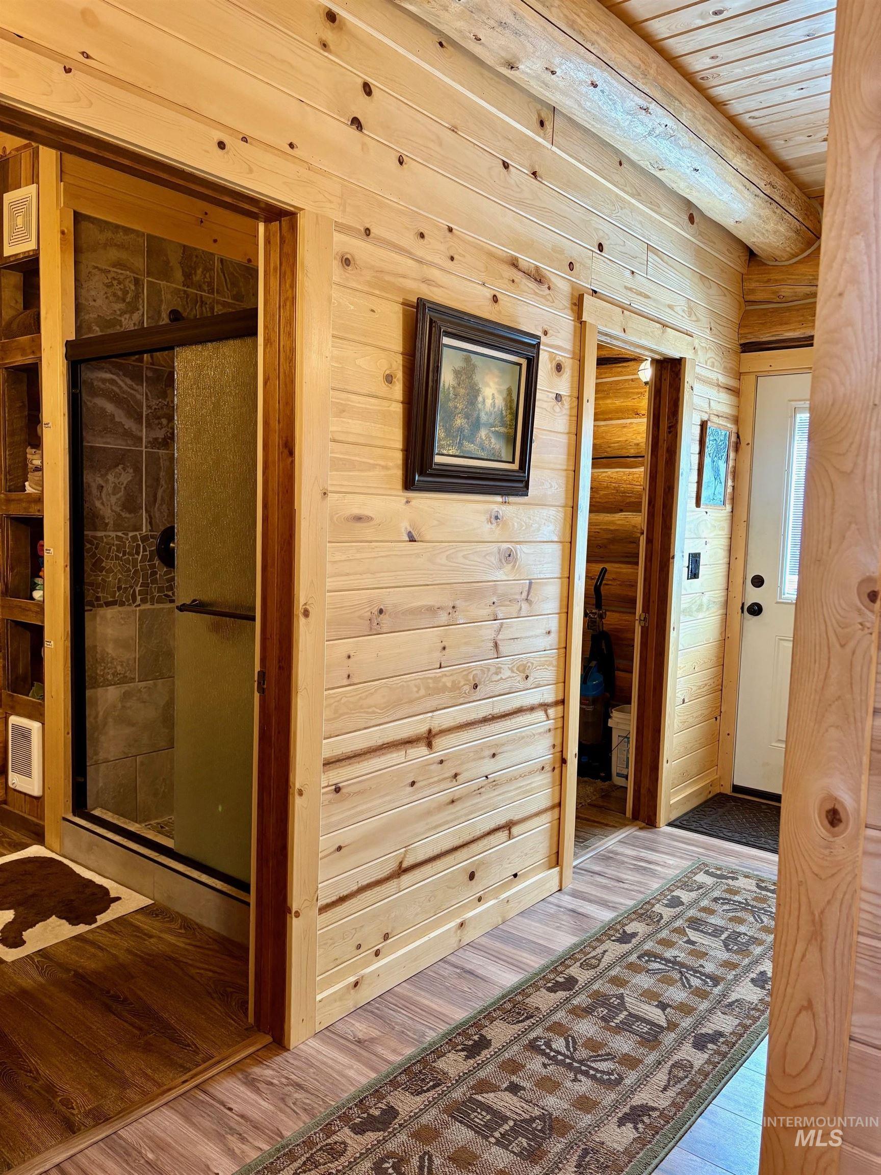 Hallway with wooden ceiling, wood finished floors, and wooden walls