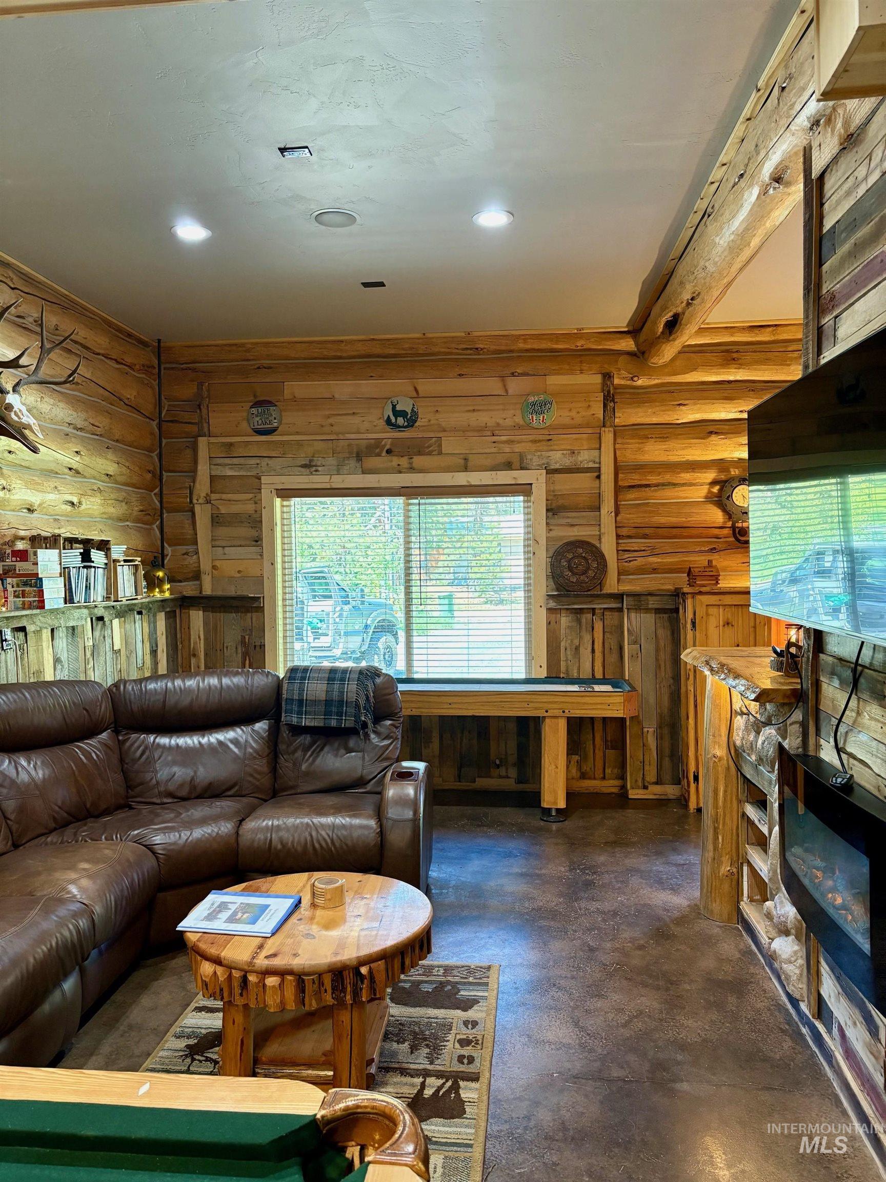Living room featuring concrete floors, log walls, and recessed lighting