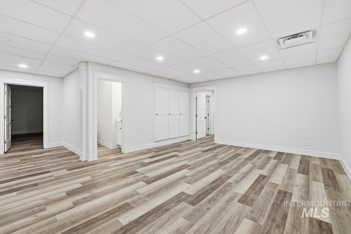 Extra Living Area could be theater/gaming room, built -in storage shelving , with a paneled ceiling, light wood-type flooring, and recessed lighting