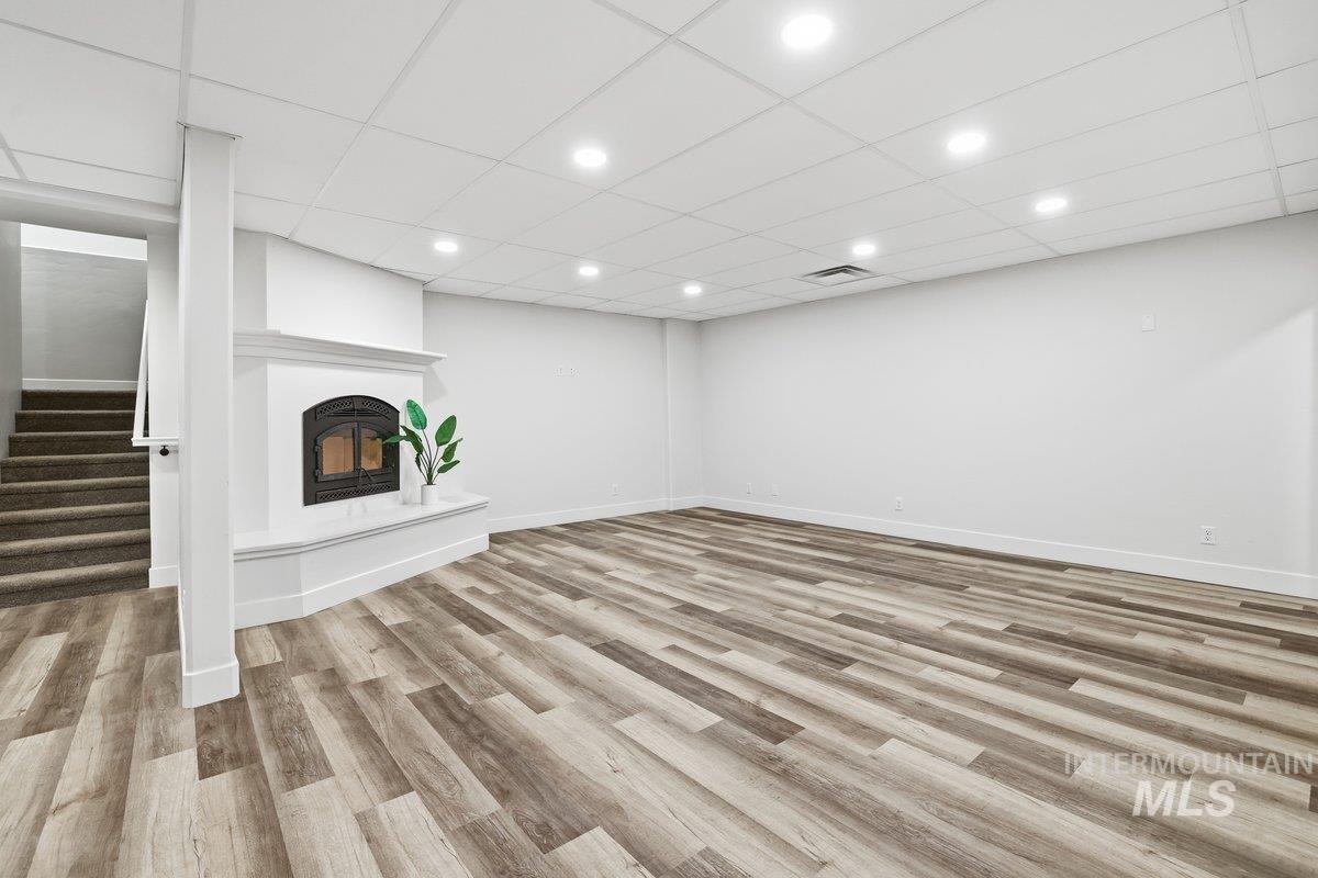 Living room with wood burning fireplace, light wood finished floors, recessed lighting, a drop ceiling and huge closet with plenty of storage.