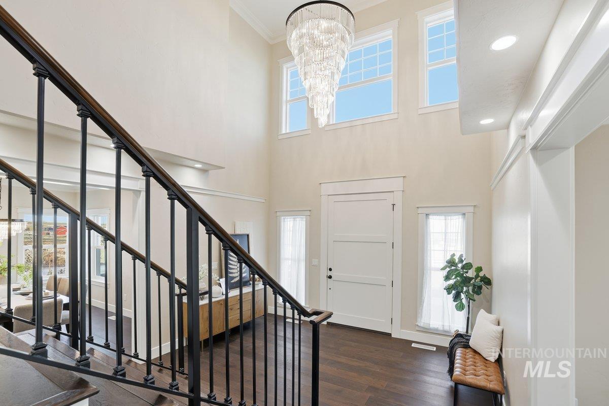 Foyer entrance featuring stairs, dark wood-style floors, a high ceiling, crown molding, and a chandelier