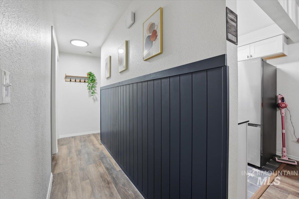 Corridor with a textured wall and light wood-type flooring