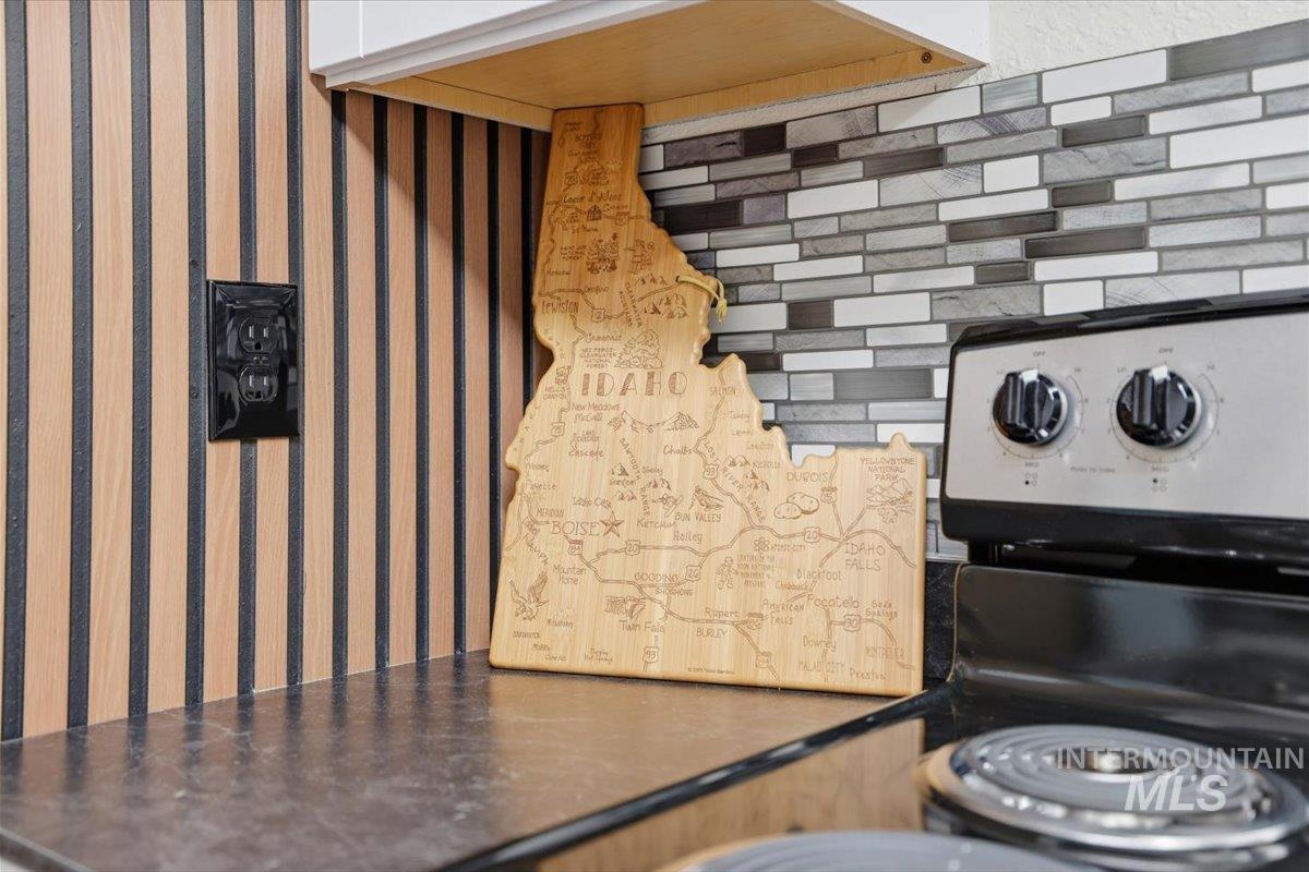 Kitchen view of wallpapered walls, dark countertops, and electric stove