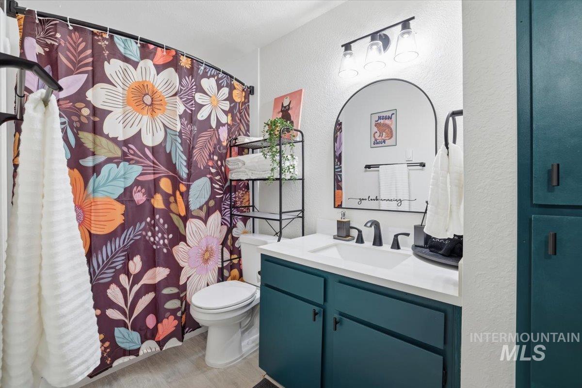 Full bath featuring a textured wall, a shower with curtain, and vanity