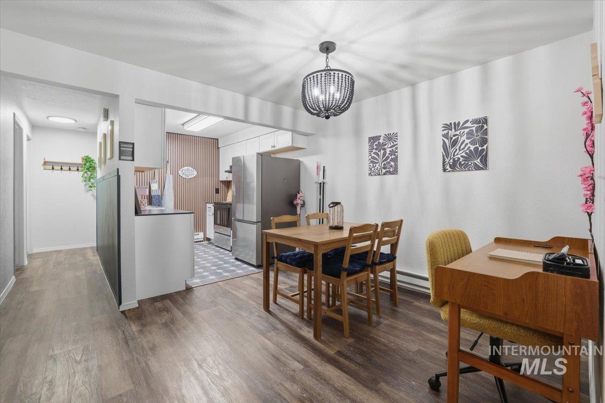 Dining space with dark wood finished floors, hanging lights, and a baseboard heating unit