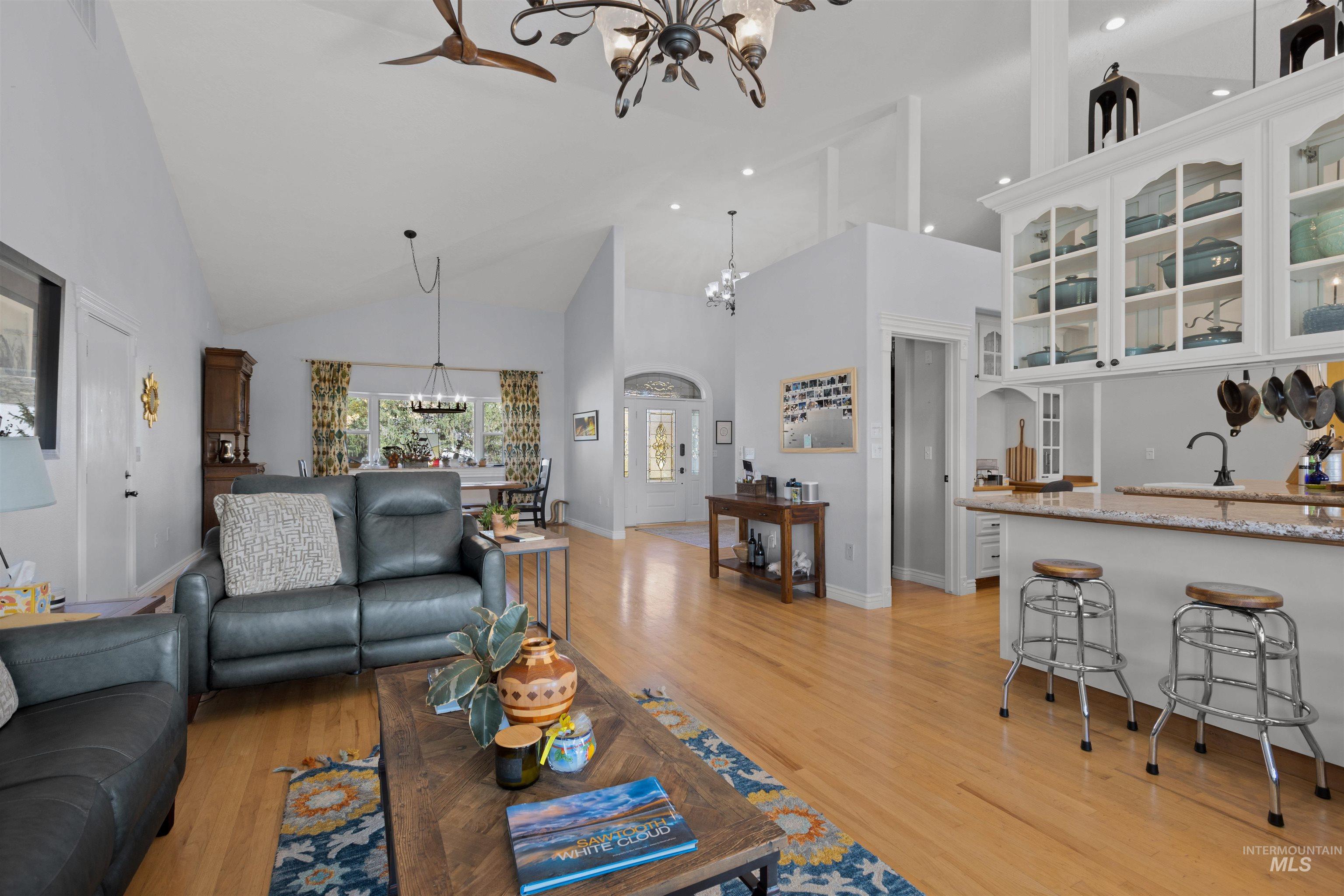 Living room with a chandelier, high vaulted ceiling, light wood-style floors, and recessed lighting