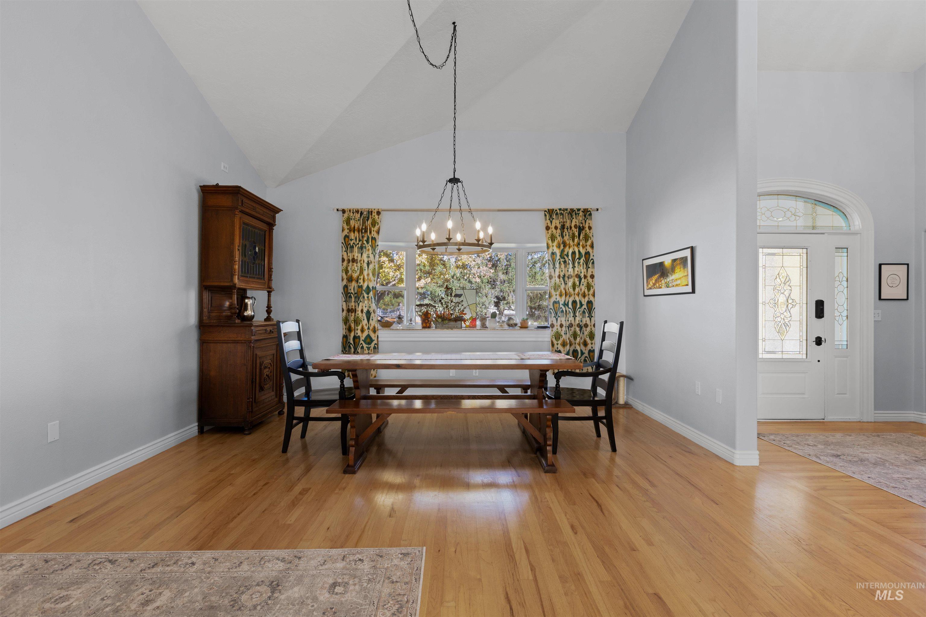 Dining room with high vaulted ceiling, light wood finished floors, and a chandelier