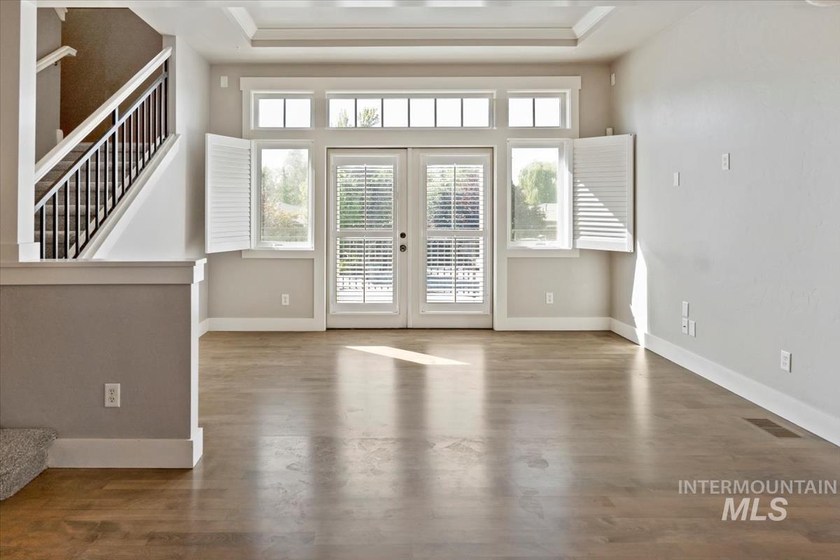 Doorway with french doors, stairs, wood finished floors, and a raised ceiling