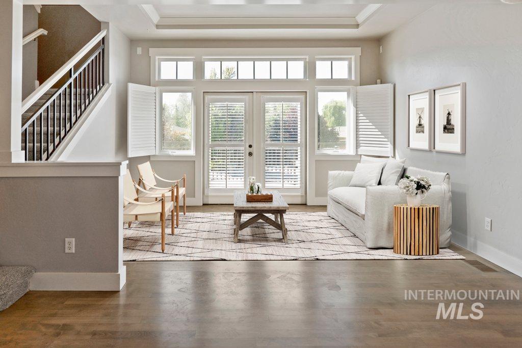 Living area featuring stairway, wood finished floors, french doors, and a raised ceiling