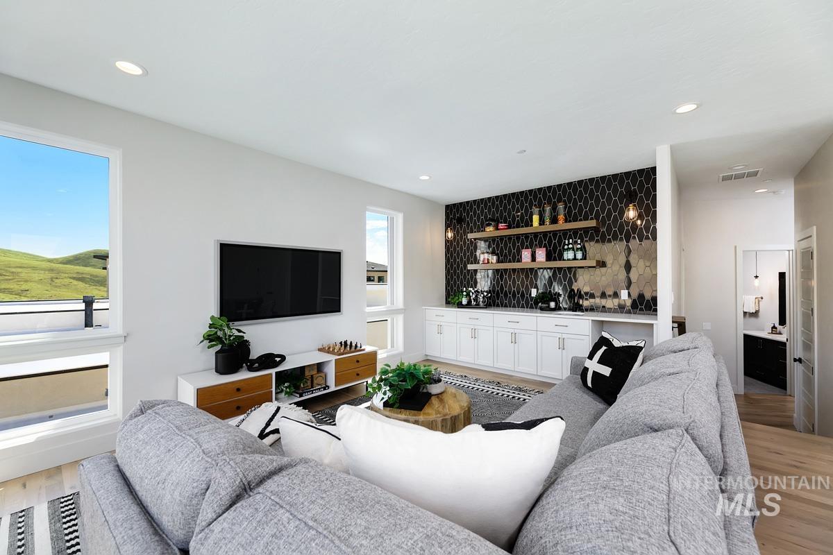 Open-concept living area featuring light wood-finish flooring, recessed lighting, and expansive windows