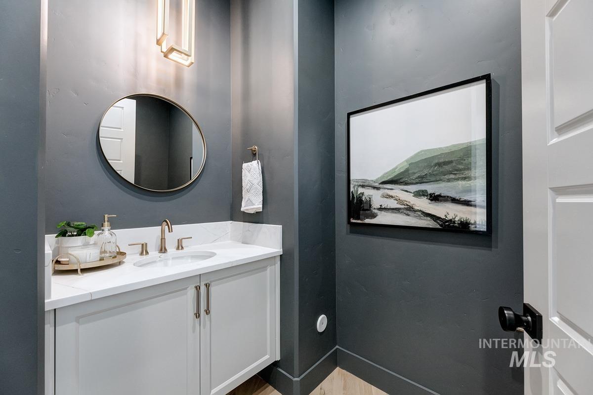 Vanity with white cabinetry, a white countertop, and gold-tone fixtures