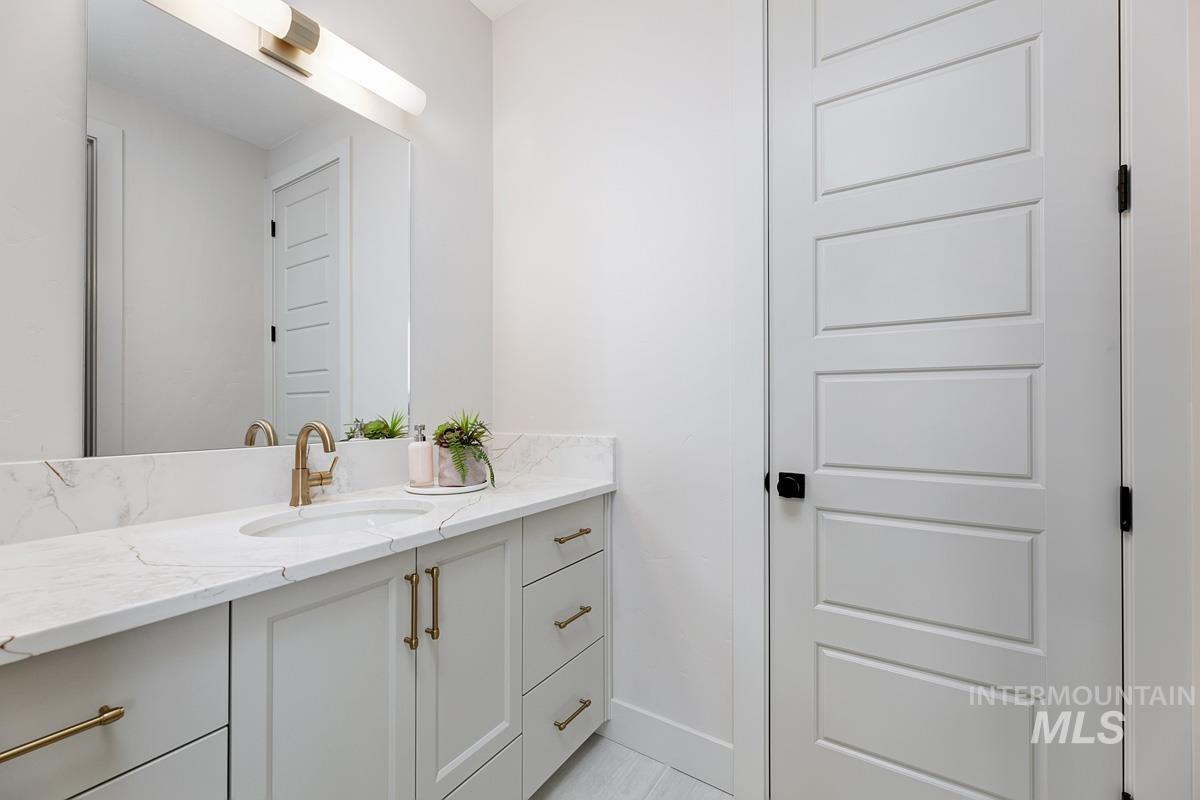 Vanity featuring a stone countertop with an integrated sink, brushed brass faucet, and coordinating hardware