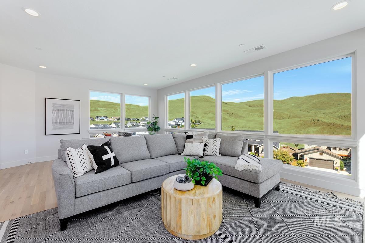 Spacious living area featuring expansive windows, recessed lighting, light wood-finish flooring, and crisp white walls
