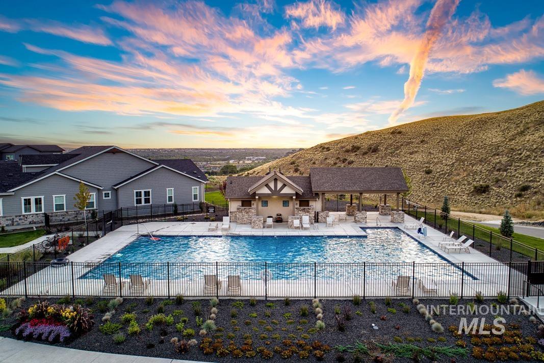 Outdoor swimming pool with an integrated spa, surrounded by a black metal fence and concrete decking