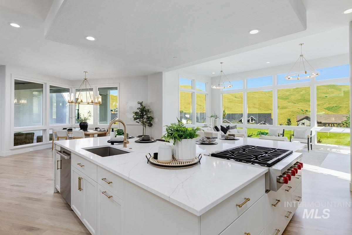 Spacious kitchen island featuring a built-in gas range, integrated sink, and white cabinetry with brass hardware