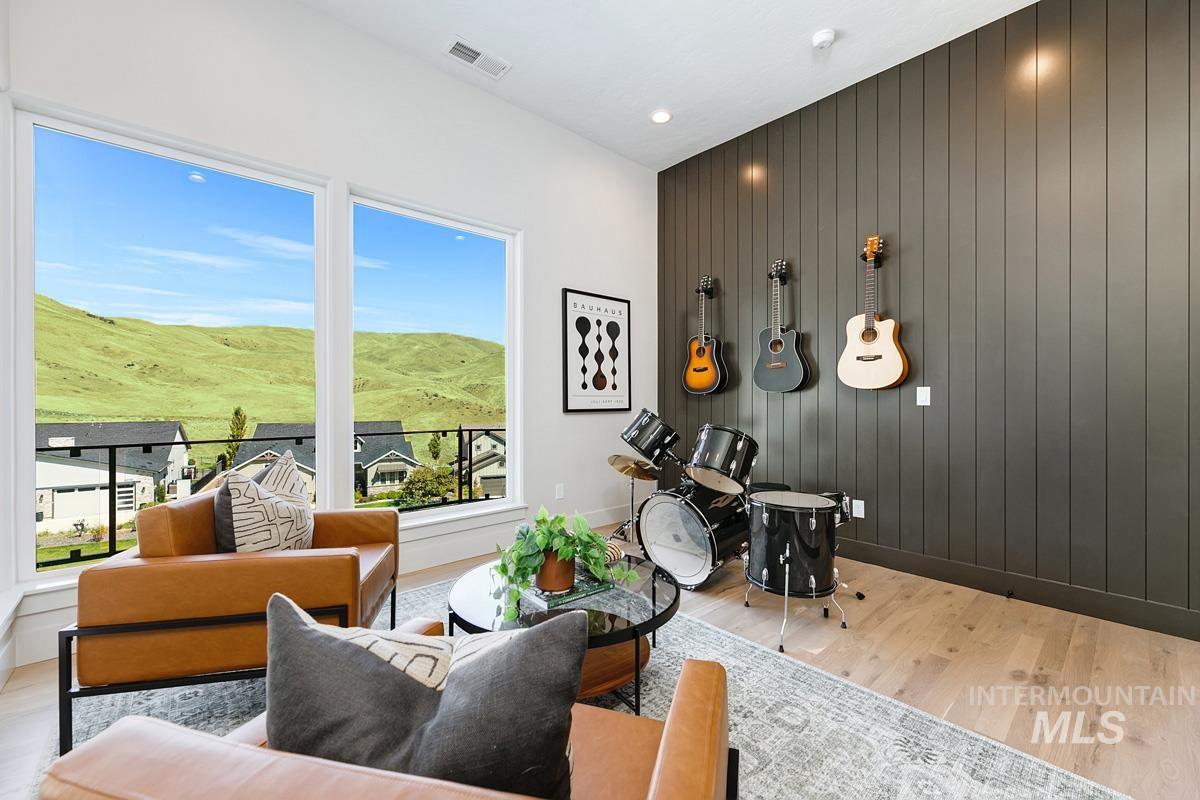 Spacious room featuring floor-to-ceiling windows, light wood-finish flooring, and a dark vertical plank accent wall