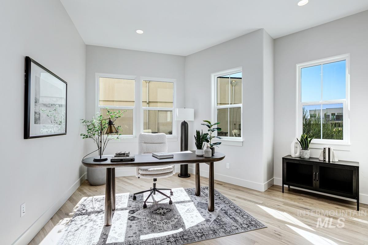 Recessed lighting illuminates this bright interior space featuring light wood-finish flooring